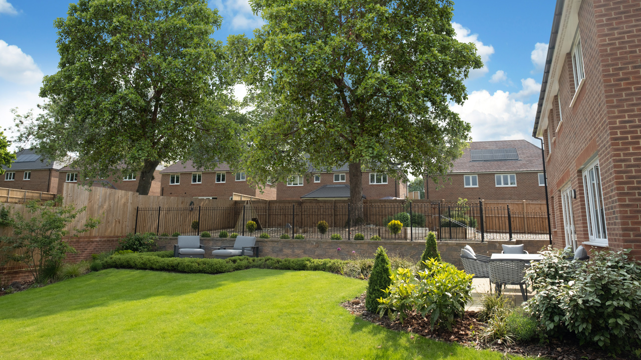 Garden with mowed lawn two large, mature trees visible behind a fence