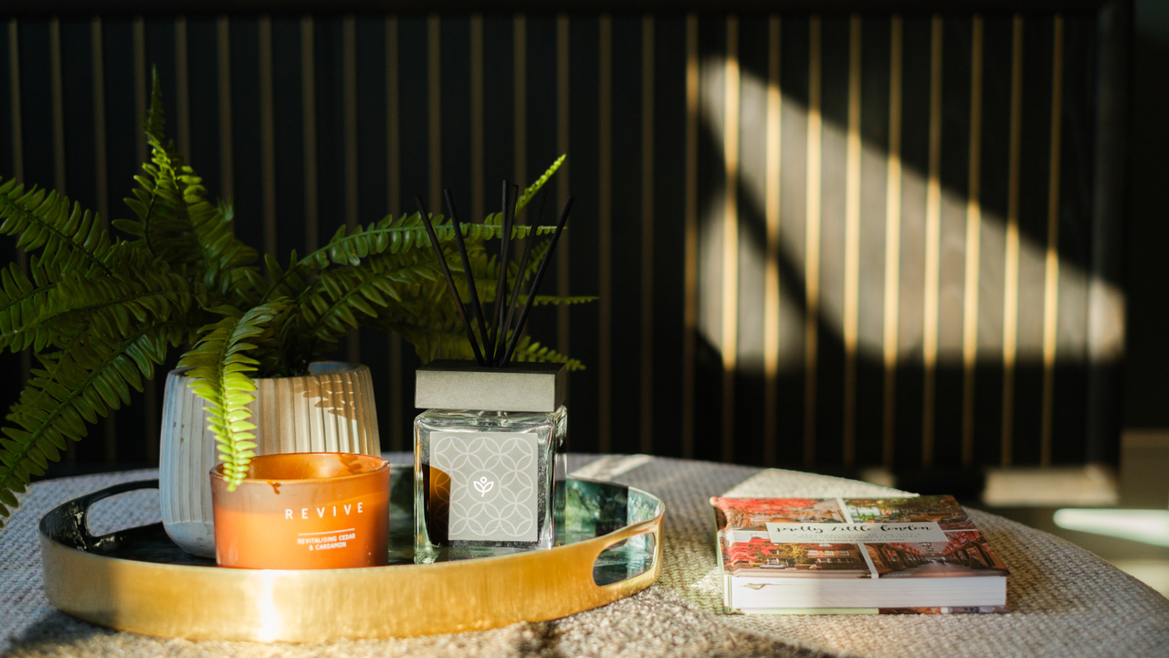 Gold try containing a plant, orange candle and Redrow-branded room spray