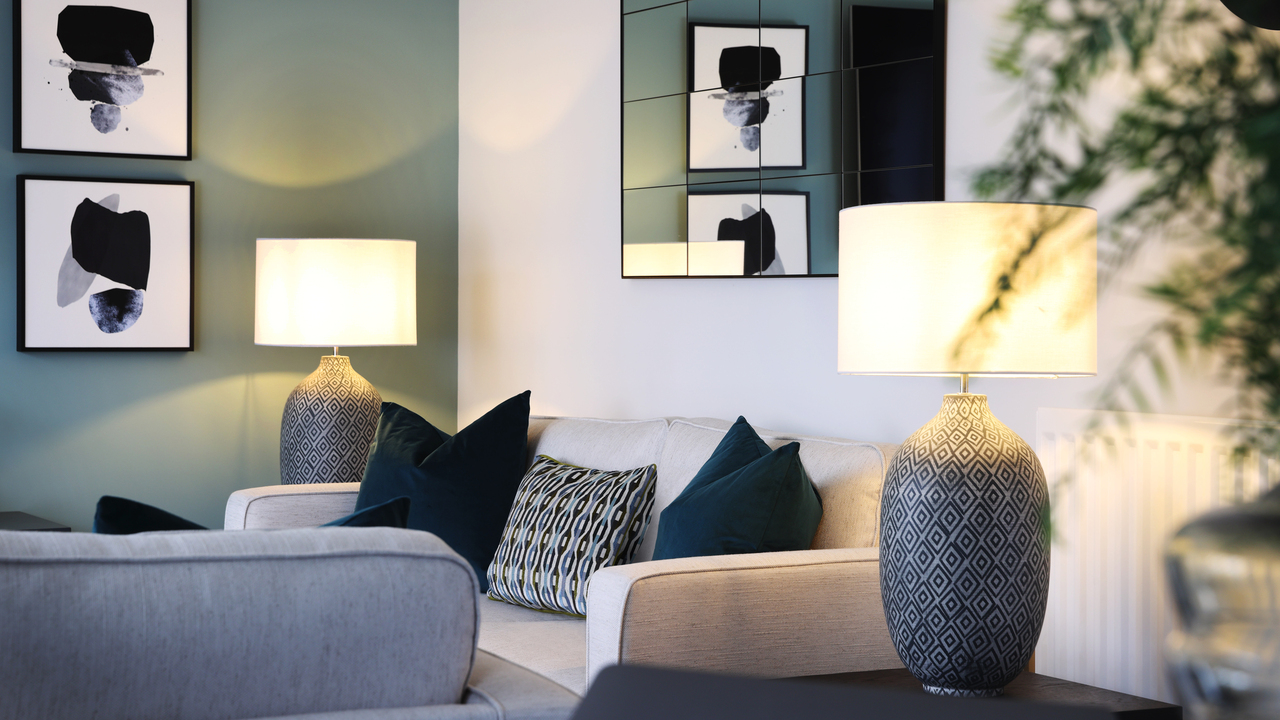 Luxurious beige sofa with navy cushions, flanked by two large patterned lamps