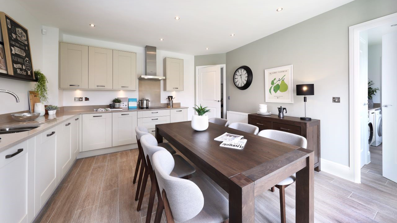 Shaker-style kitchen with light units, pale green walls and a dark wood dining table