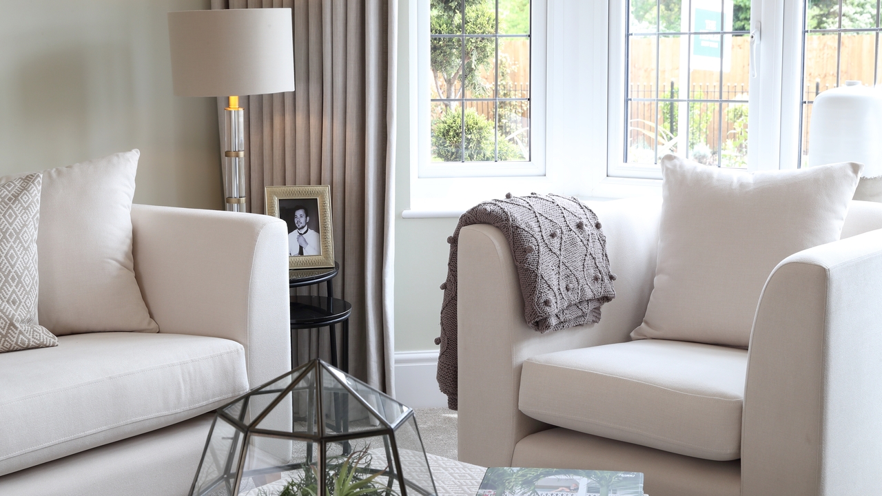 Cream sofa and chair with a cosy brown blanket over the arm