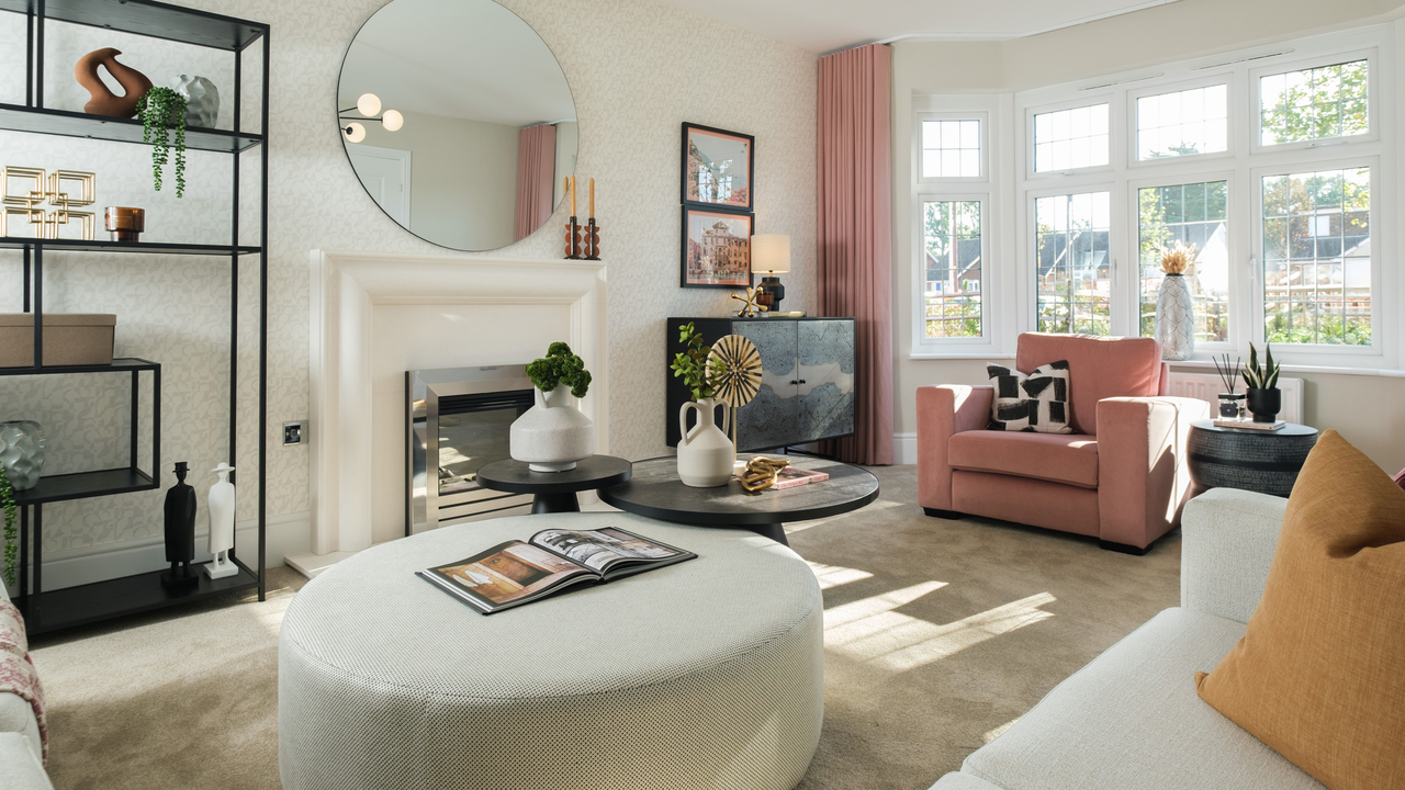 Cosy lounge with a large foot pouffe and lots of natural light streaming through a bay window