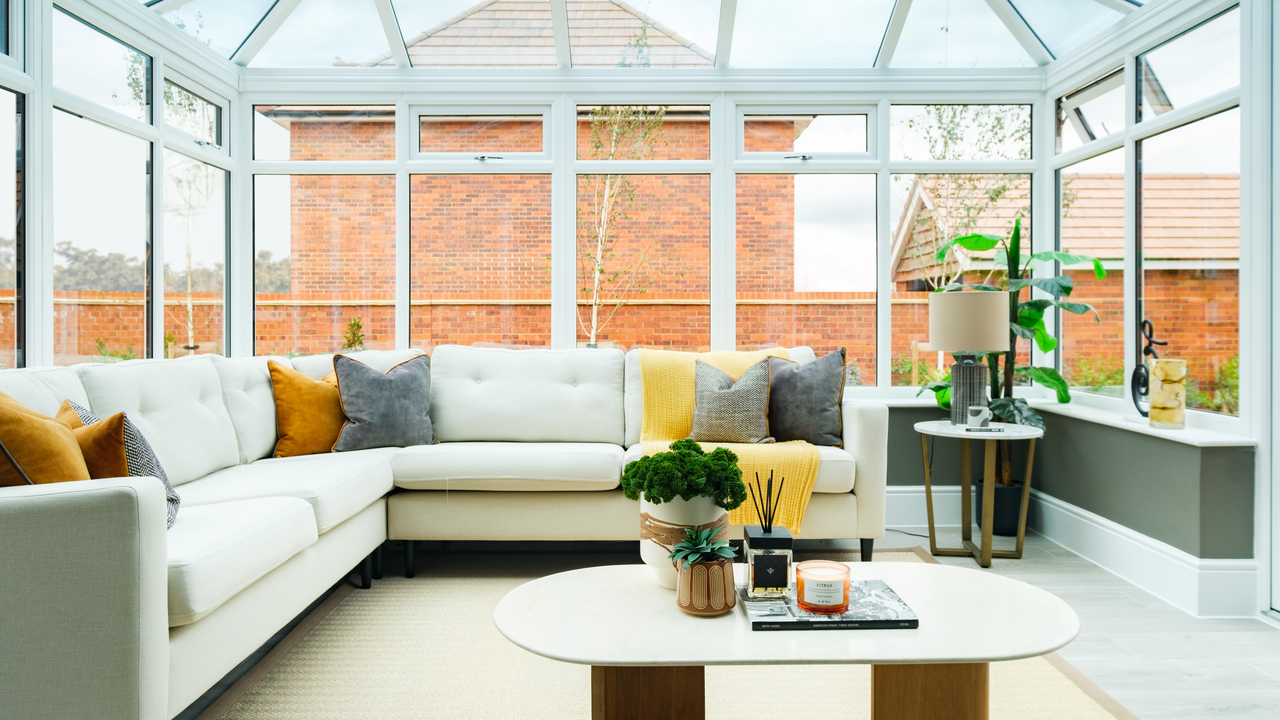 White corner sofa with colourful scatter cushions in a light-filled garden room