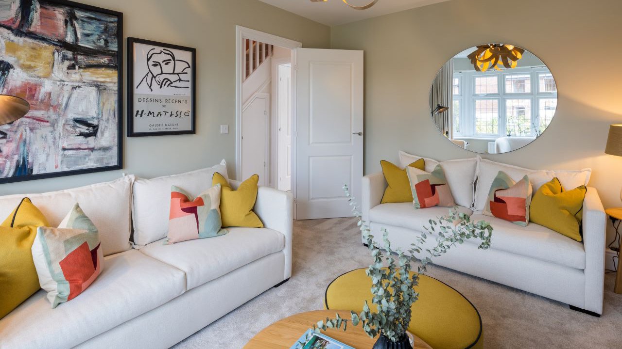 Living room with cream sofas and ochre scatter cushions and foot pouffe