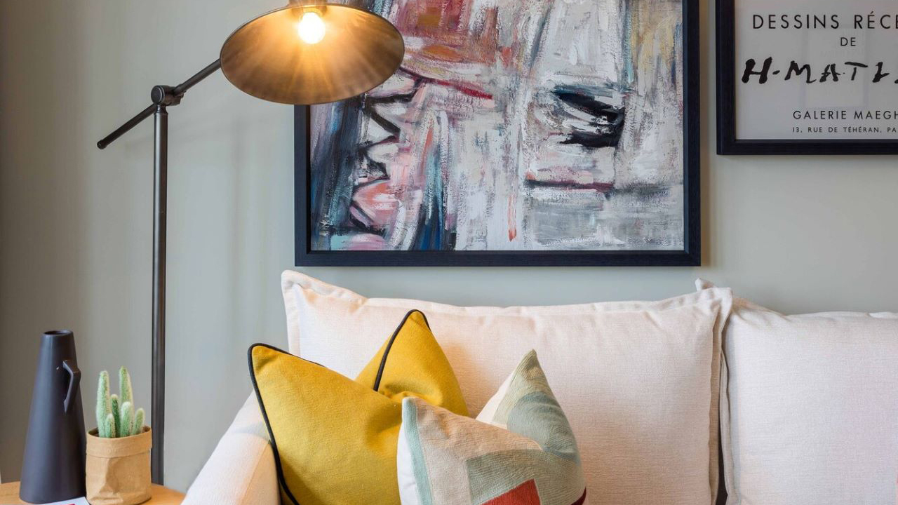 Lever arm floor lamp shining over a cream sofa with ochre cushions