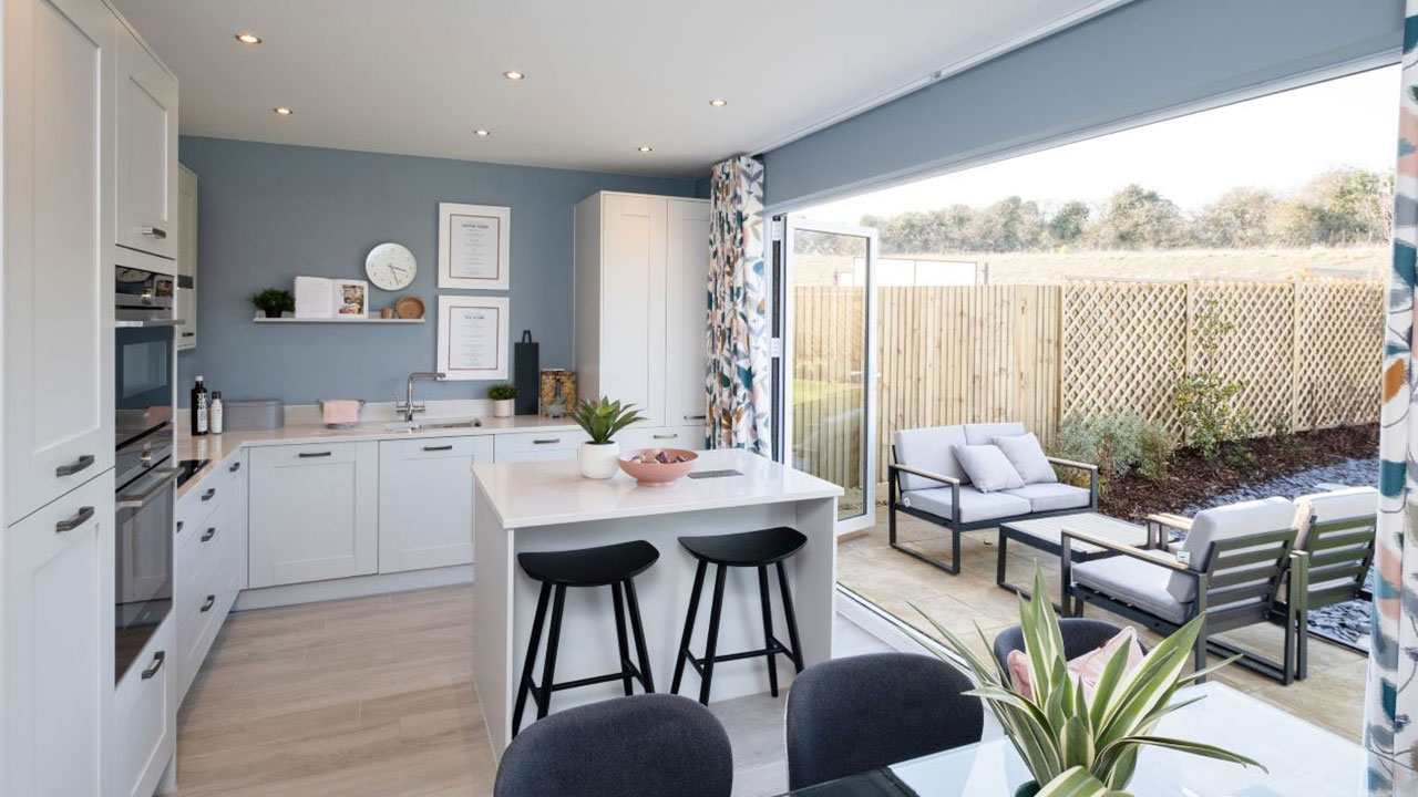 Open plan kitchen with bi-fold doors open to reveal outside seating in the garden
