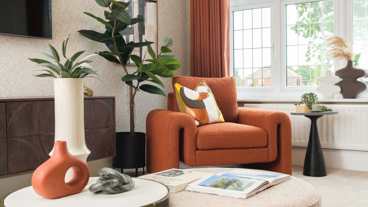 Sculptural orange accent chair in a bay window, surrounded by plants