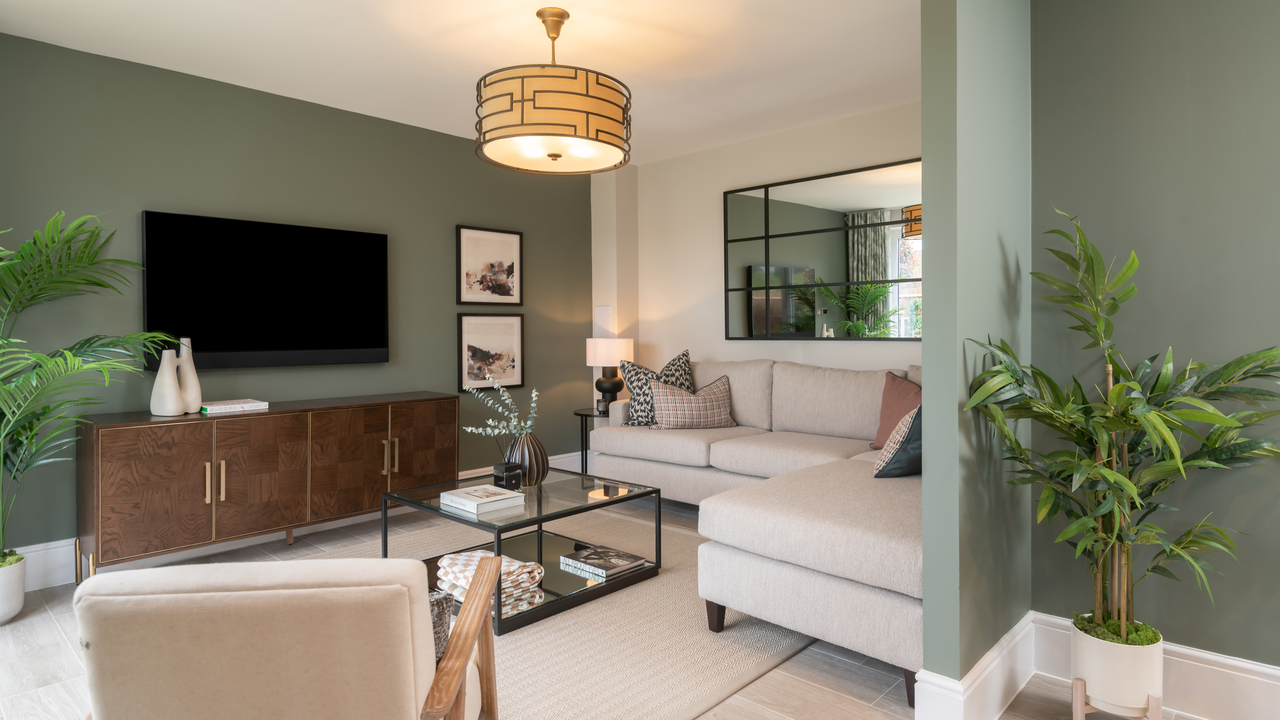 Open plan family area with green walls and cream corner sofa