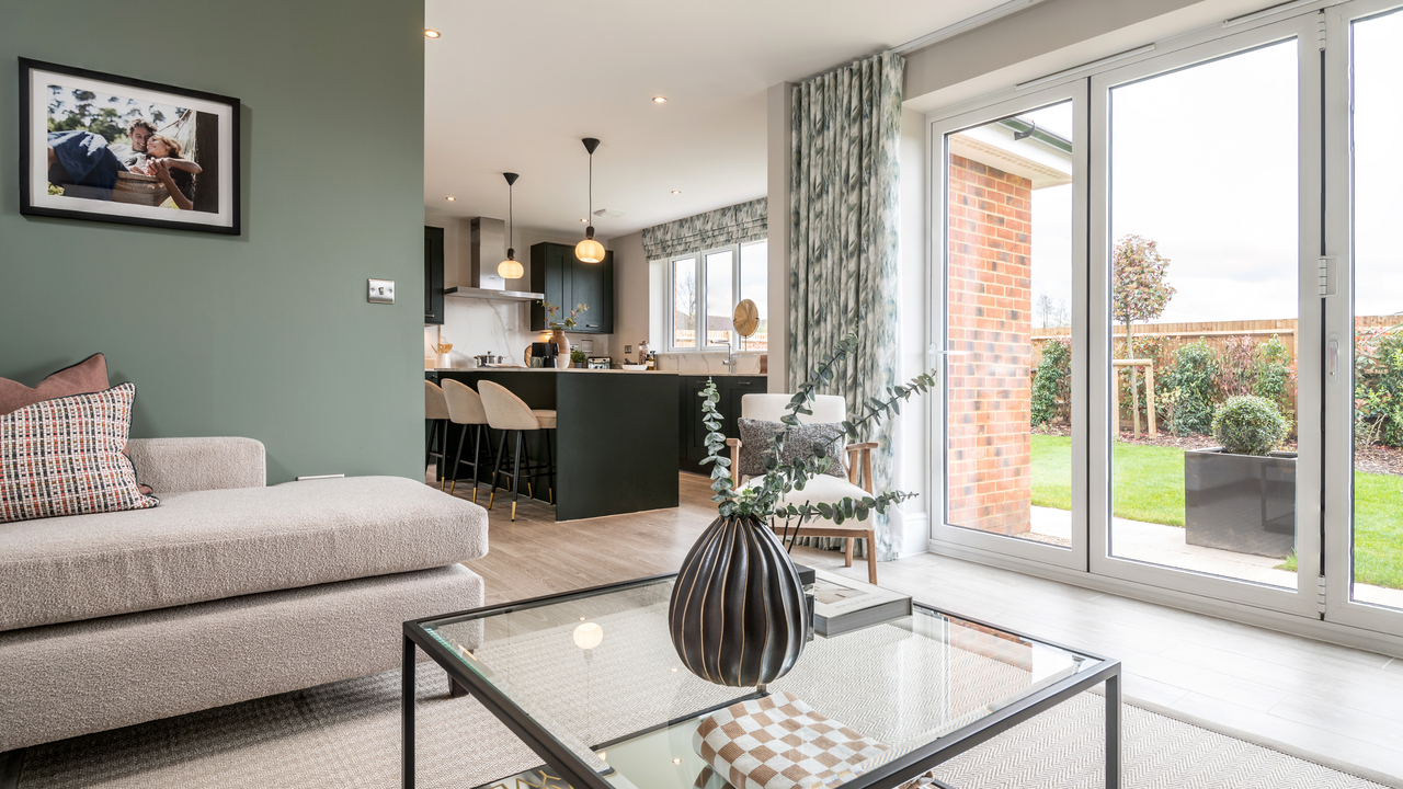 Open plan living area with large patio doors leading to the garden and a stylish blue kitchen visible in the background