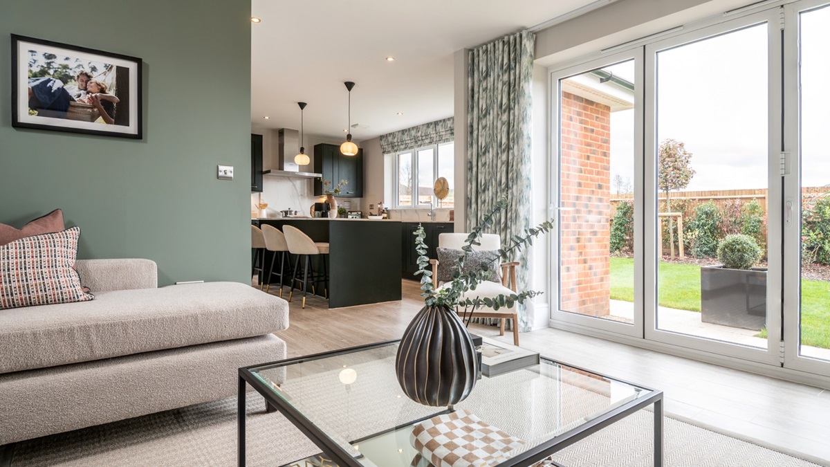 Open plan living area with large patio doors leading to the garden and a stylish blue kitchen visible in the background