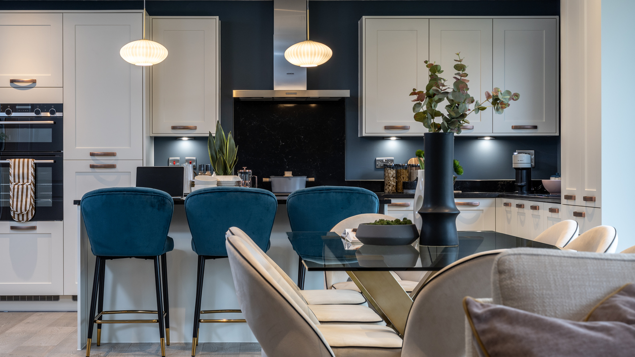 An open plan kitchen and dining dining area featuring blue bar stools and pendant lighting over a kitchen island 