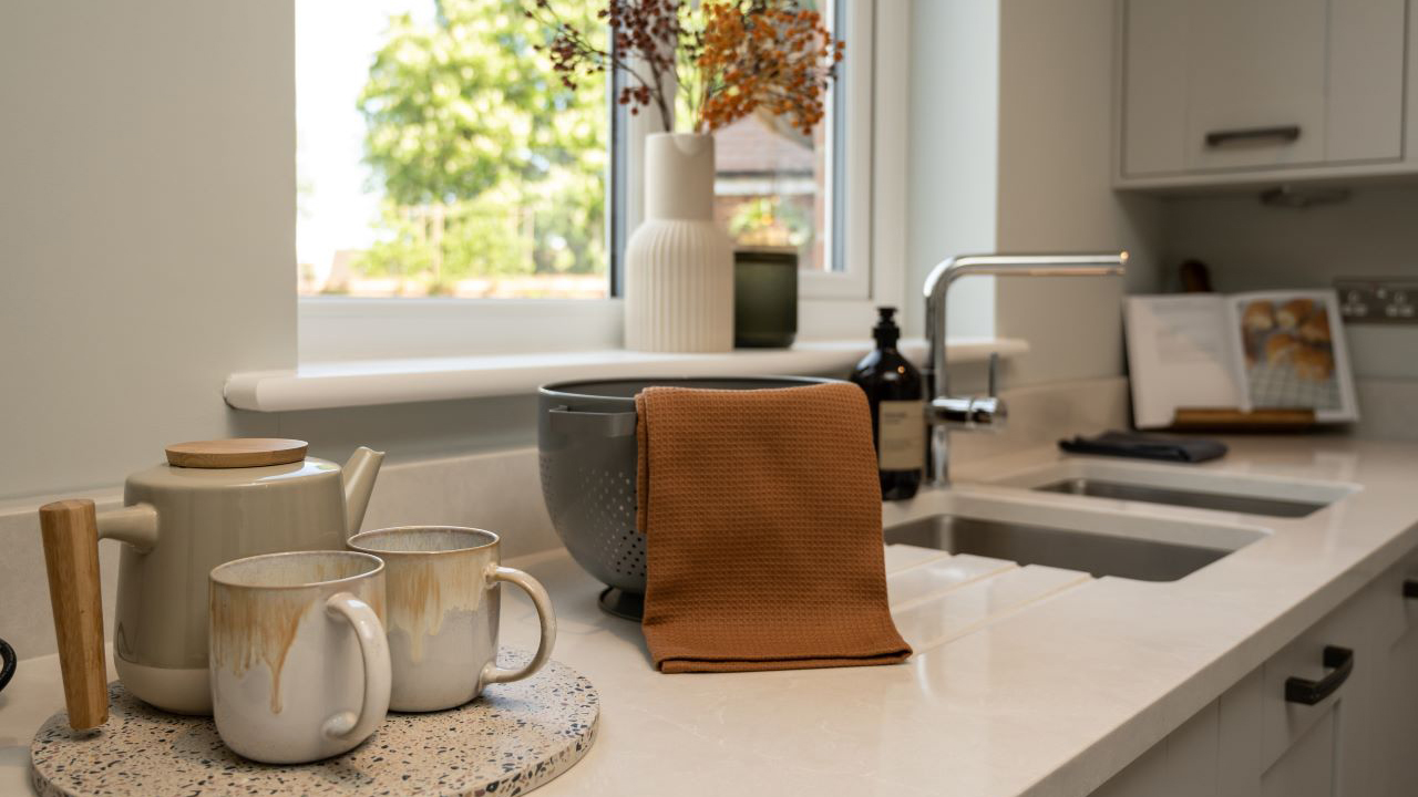 Kitchen worktop with a rustic tea set and a brown tea towel draped over a colander