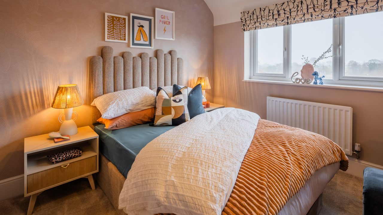 Pink bedroom with a stylish padded headboard and lamps on either side of the bed