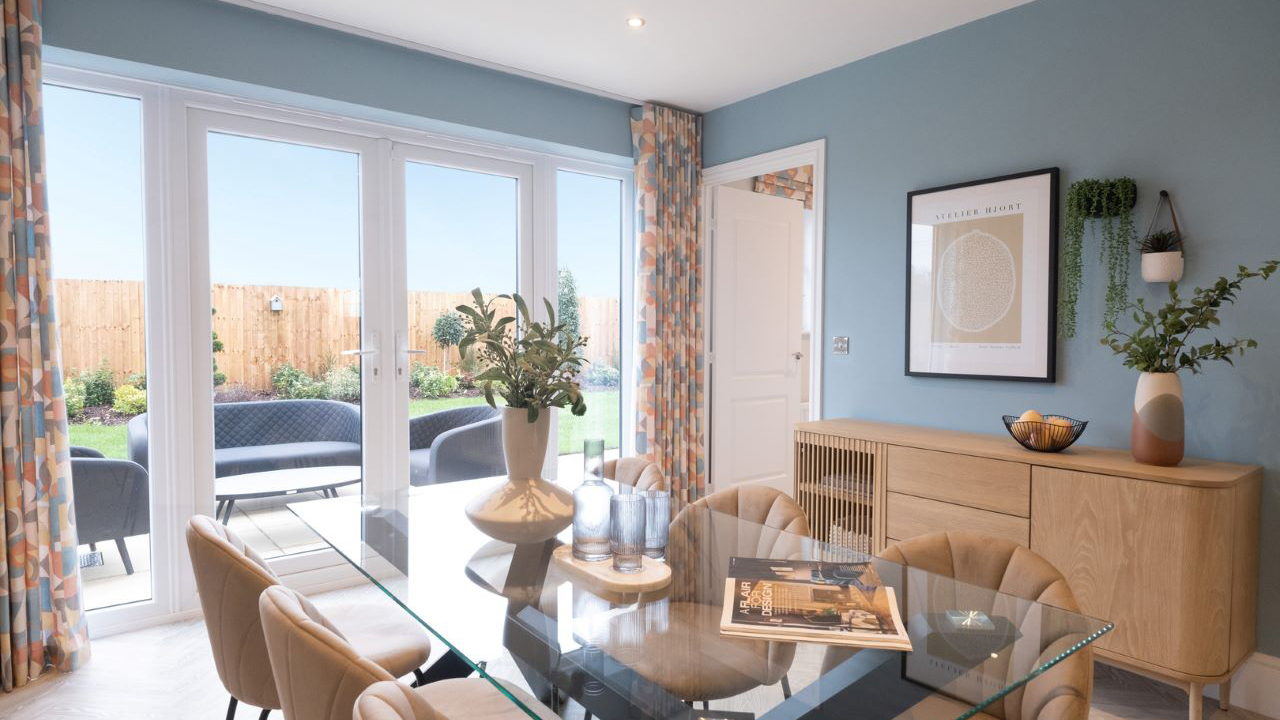 Dining room with blue walls, glass dining table and large patio doors leading out to the garden
