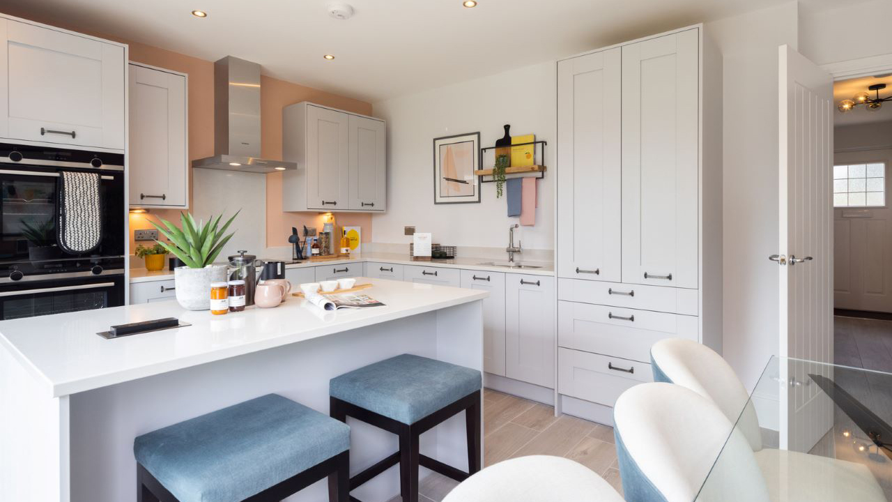 Shaker kitchen in soft grey tones, featuring a breakfast bar accompanied by two blue velvet bar stools