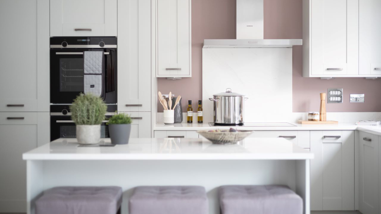 Elegant shaker kitchen with warm mineral grey units and dusty pink walls
