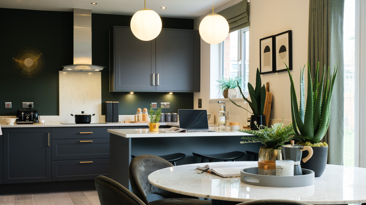 Kitchen units in inky tones, with stunning pendant lights hanging over a breakfast bar
