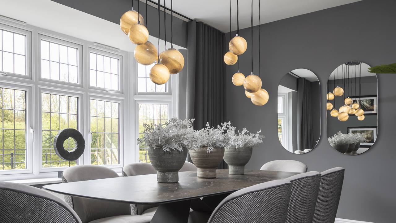 Grey dining room with statement pendant globe lights hanging over a large table