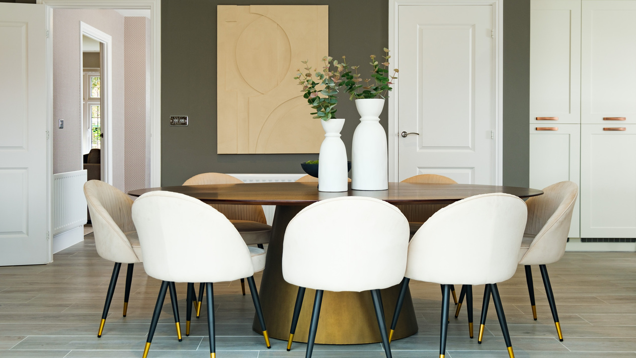 Chic dining room with circular gold table surrounded by cream bucket chairs