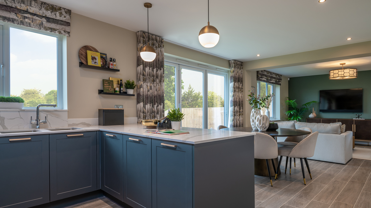 Open plan kitchen dining area with blue units and long gold pendant lights over a breakfast bar