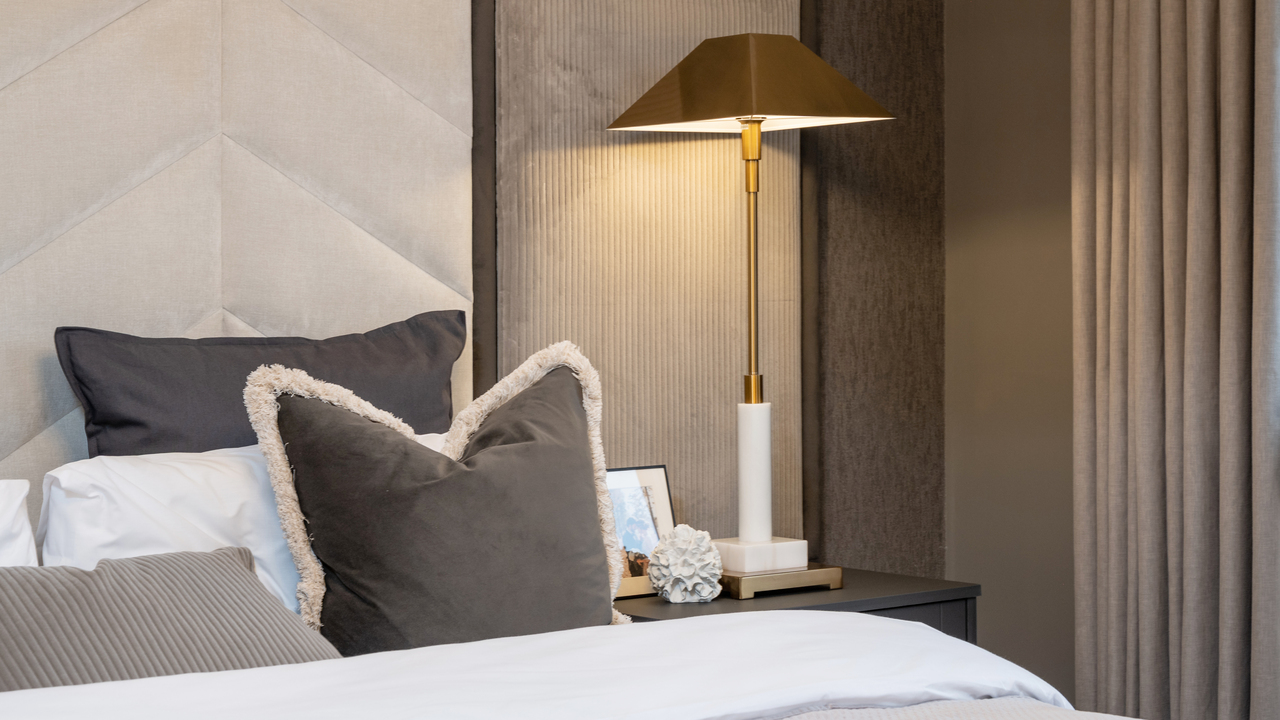 Bed, bedside lamp and heavy curtains in earthy brown tones