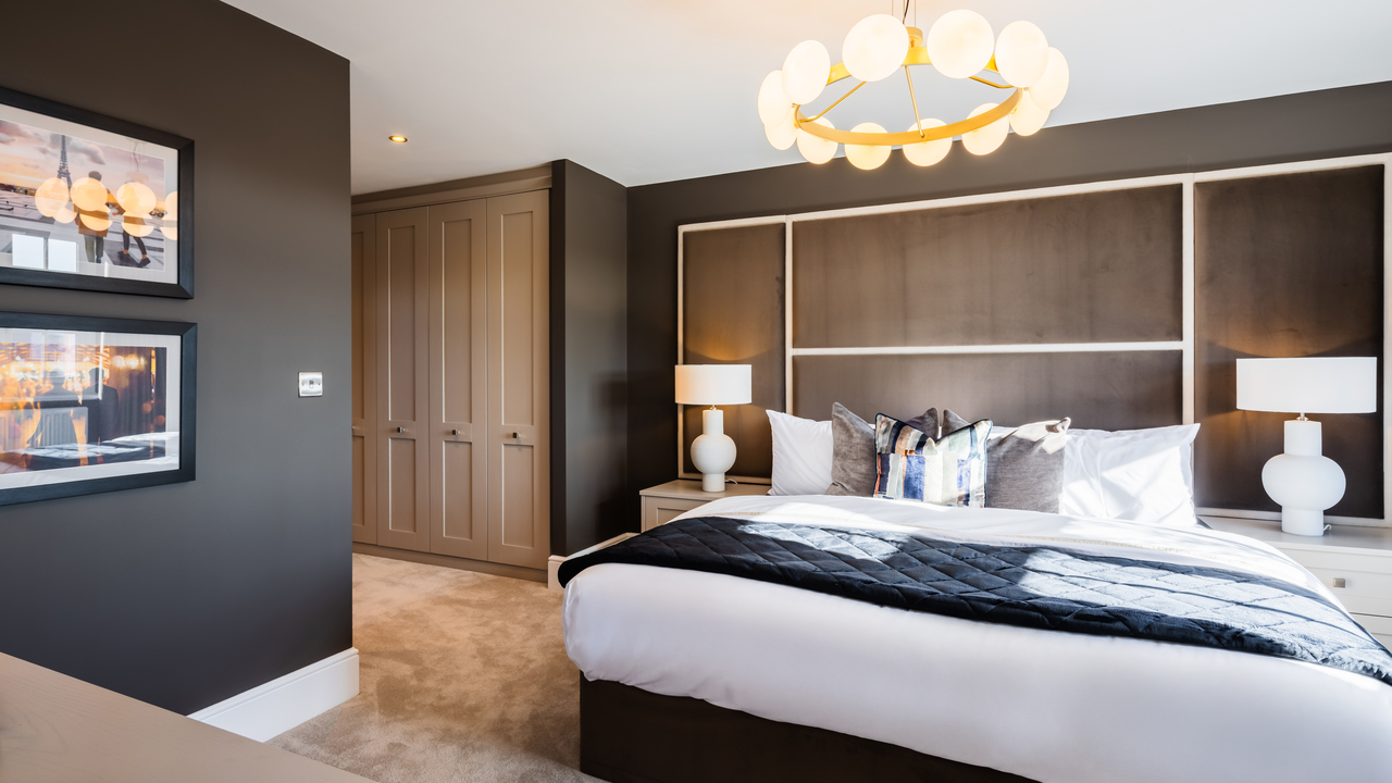 Bedroom with textured headboard, dark walls and walk-through wardrobes