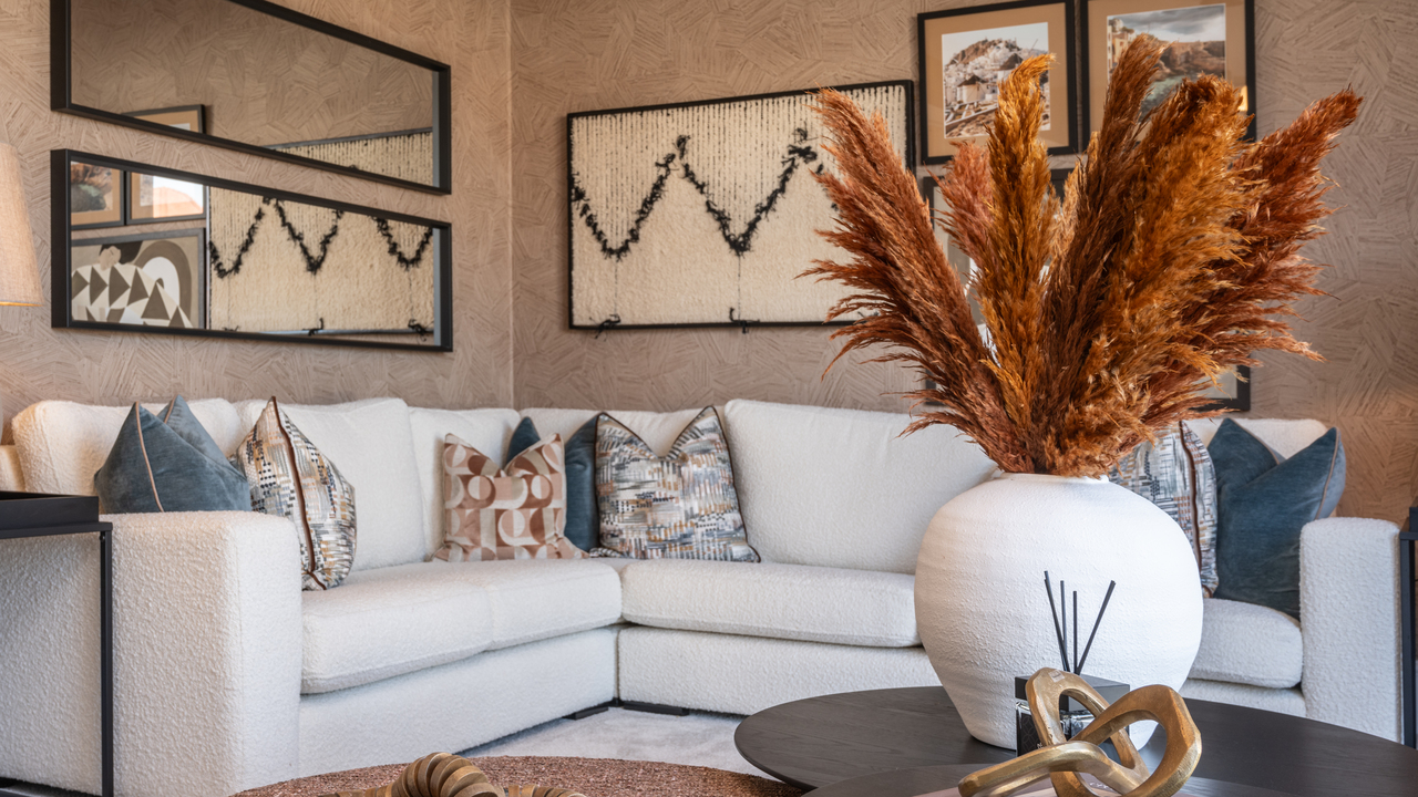 Cream corner sofa and rust coloured pampas grass on a dark wood coffee table 