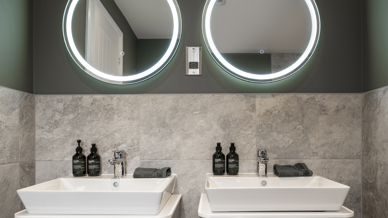 Two bathroom sinks with lighted mirrors