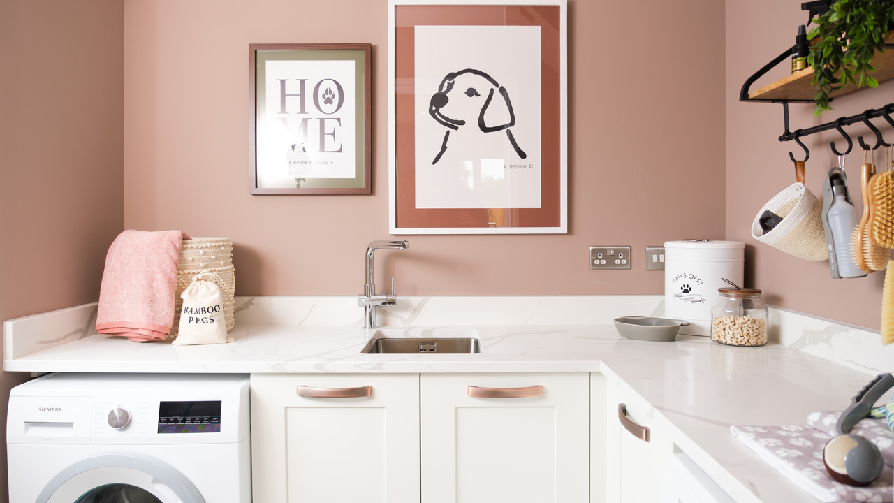 Pink utility room with white cupboards and framed artworks