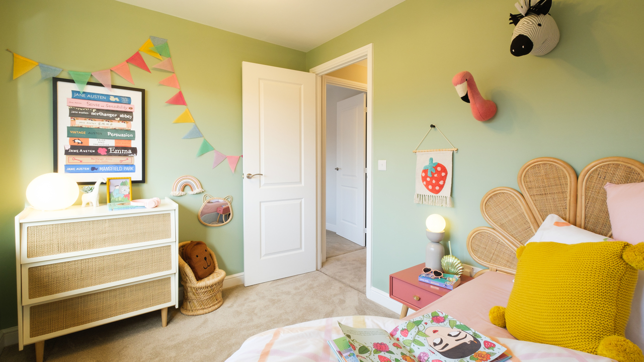 Colourful kids' room with bunting, wall-mounted stuffed animals and wicker fan headboard
