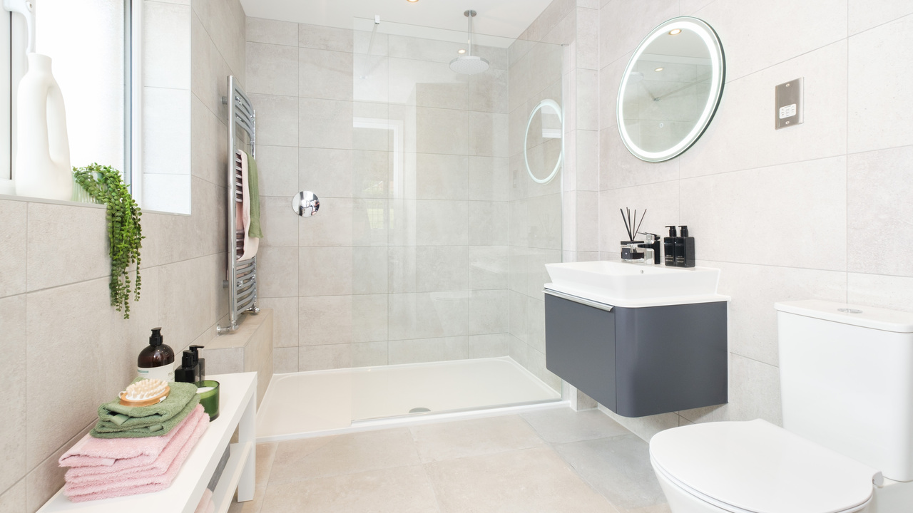 Beautiful tiled shower room with pink and green towels neatly folded on a bench