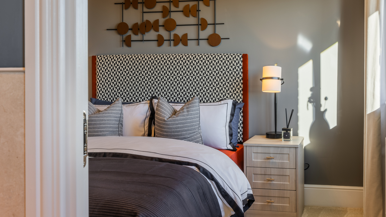 Double bed with patterned headboard next to lamp on a bedside table