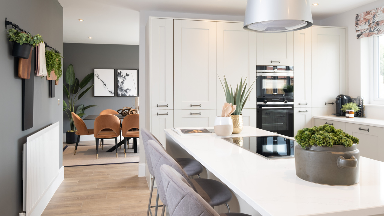 Grey barstools next to a kitchen island with potted plants on top