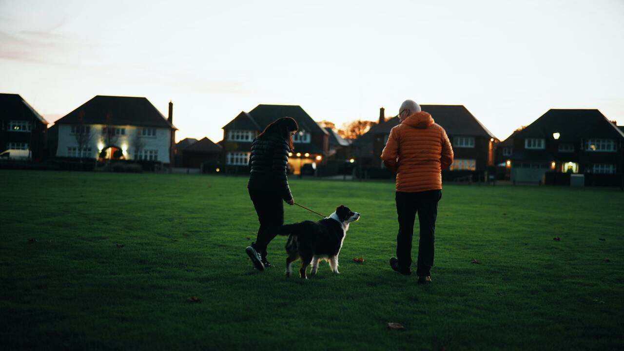Paralympian Menna Fitzpatrick walking her dog on an area of green space at dusk