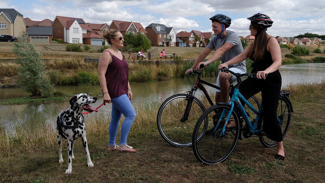 Two people on bikes chat with a dog walker