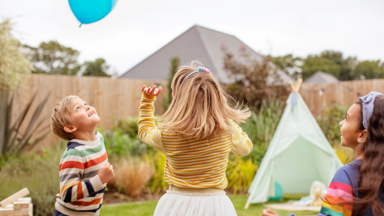 Children playing with a balloon in the garden of their Redrow home