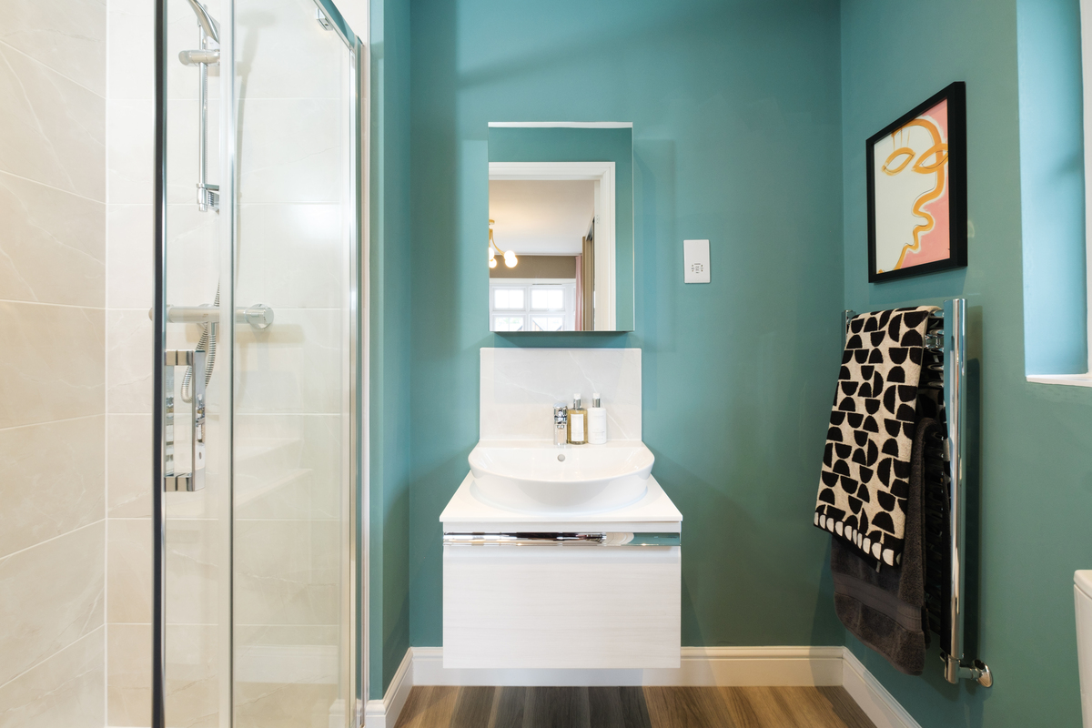Bathroom sink on top of a storage cupboard in a shower room with jade walls
