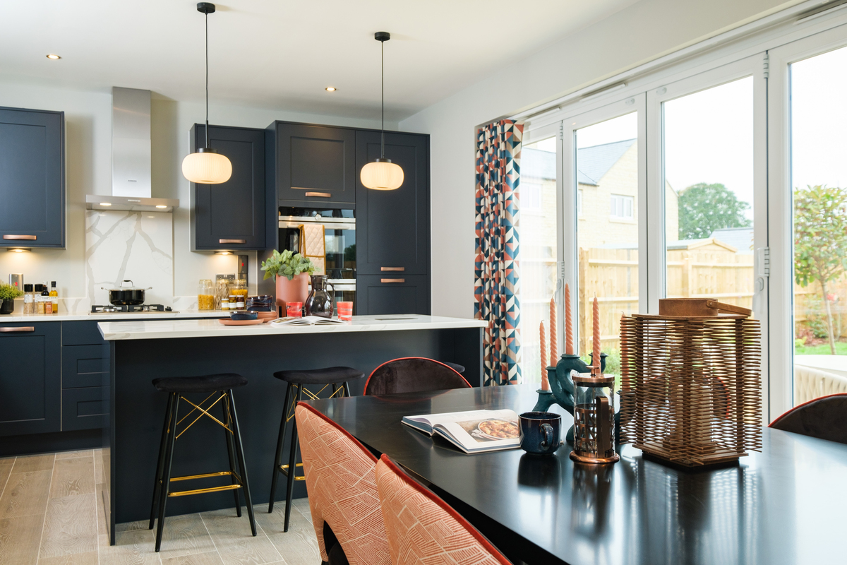 Open plan kitchen dining area with dark units and two pendant lights hanging over a breakfast bar