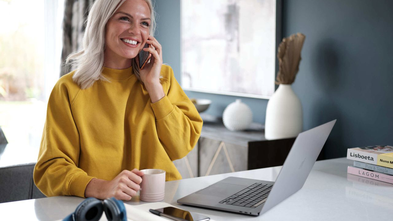 Woman talking on a mobile phone while using her laptop