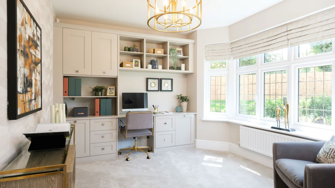Home office with large bay window and fitted desk and storage