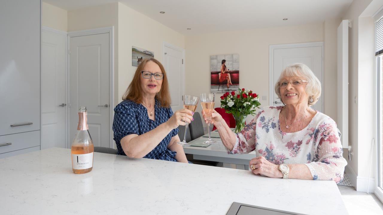 Two women saying cheers with glasses of rose in a Redrow kitchen