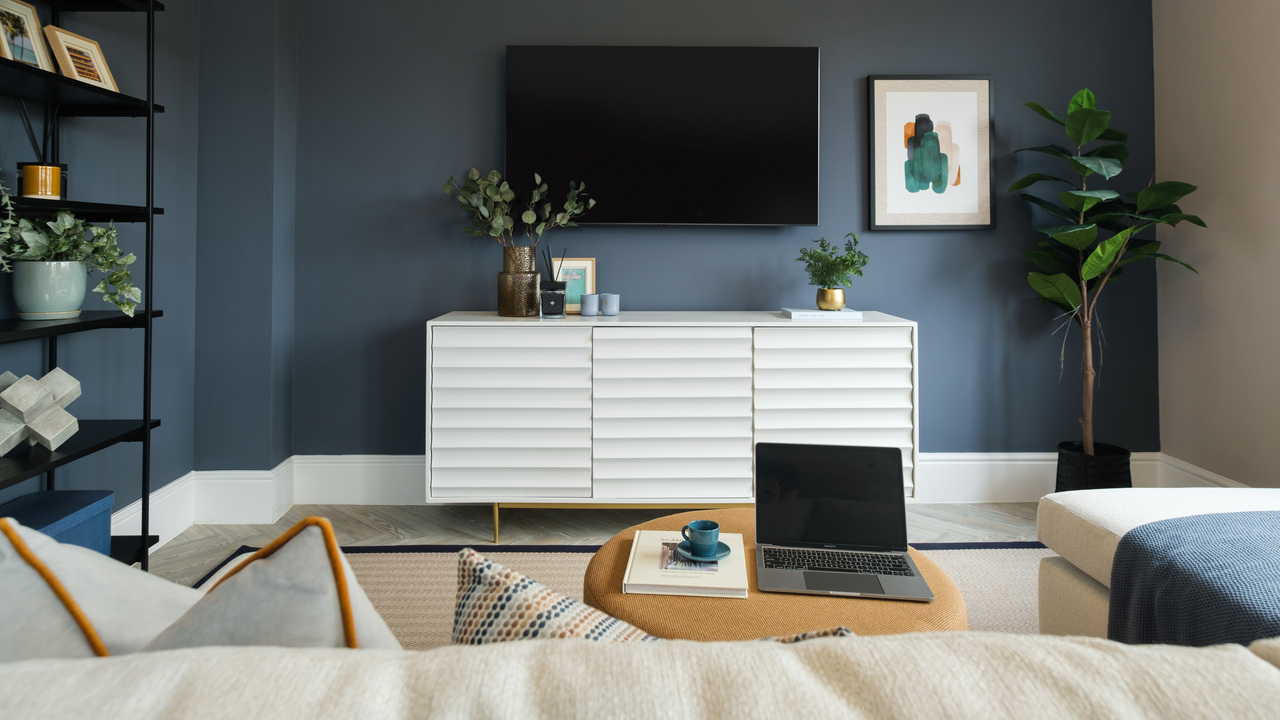 Family room with navy blue walls, white sideboard and lots of plants