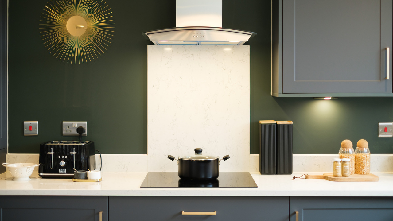 Pan on an induction hob in a kitchen with dark units and walls