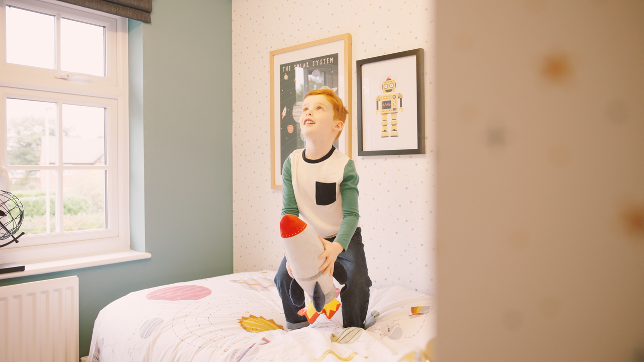 Boy holding a toy rocket and bouncing on his bed