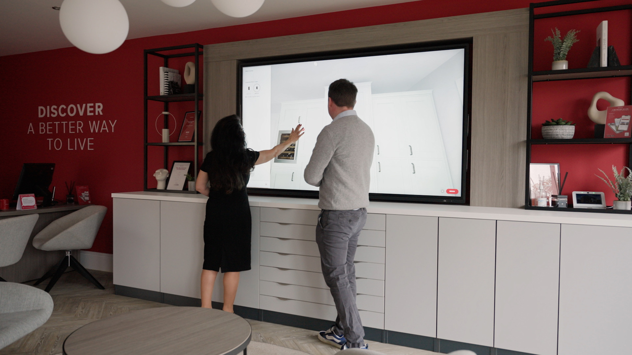 Two people looking at a kitchen visualiser in a Redrow Customer Experience Suite