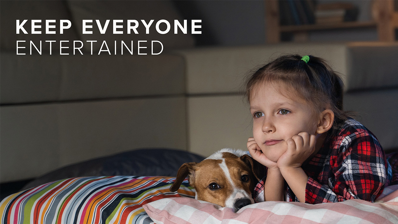 Girl and dog lay on bed watching TV, with "Keep Everyone Entertained" written over the top