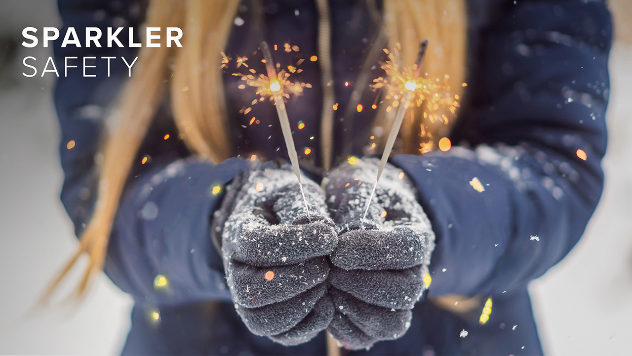 Someone holding sparklers wearing gloves. "Sparkler Safety" is written over the top.
