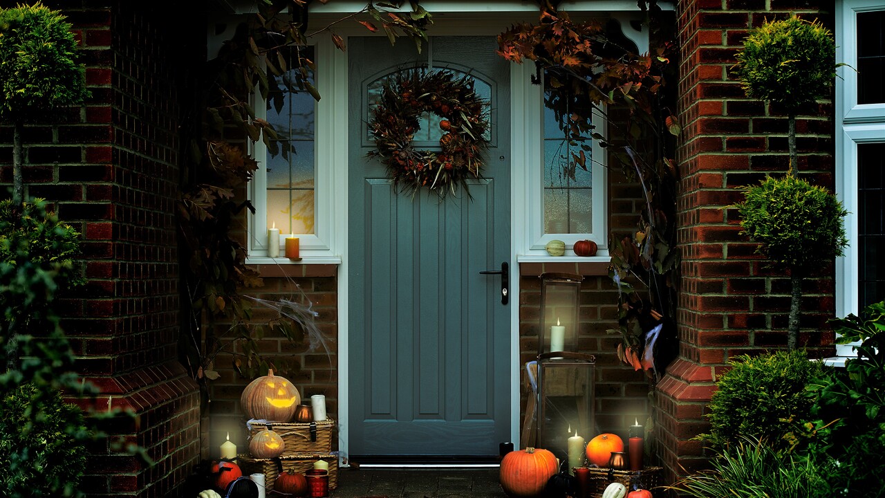 Front door decorated for Halloween with a wreath and pumpkins