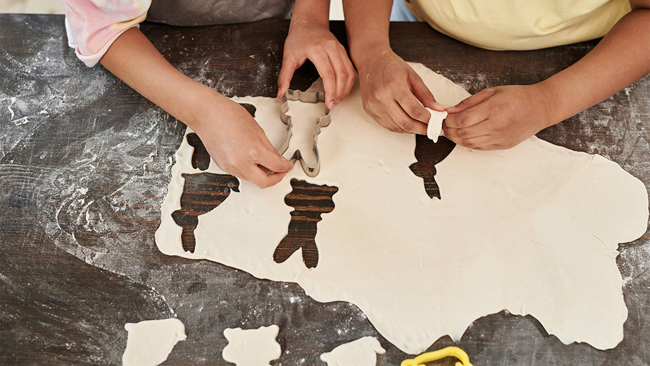 Children using a bunny-shaped cookie cutter in a sheet of dough