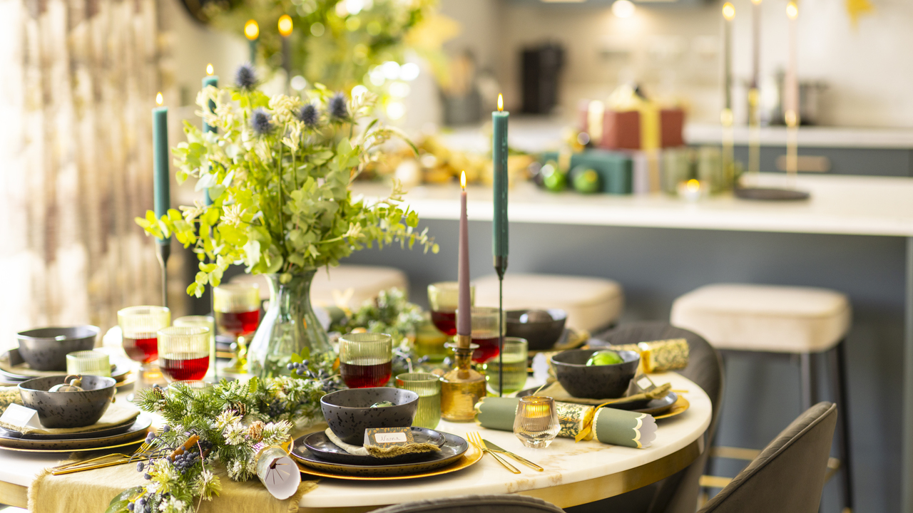 Dining table laid out for Christmas with foliage and tall candles